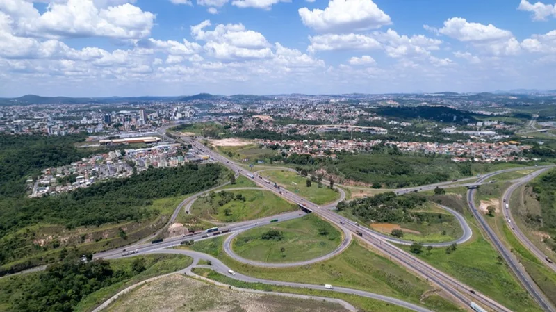 Rodovia cortando Betim vista de cima, com galpões e bairros ao redor